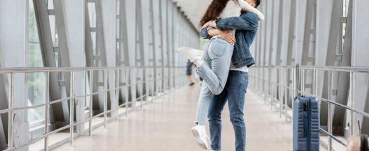 Long-Awaited Meeting. Romantic Young Arab Couple Embracing At Airport After Arrival, Excited Middle Eastern Guy Lifting Up His Girlfriend In Air While Standing Together At Terminal Hallway